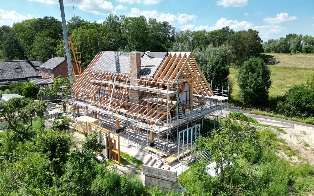 Een casco woning in aanbouw, met de houten dakconstructie op de steigers
